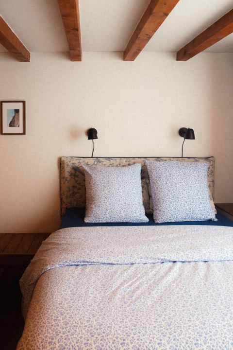 Chambre au lit fleuri sous les poutres apparentes
